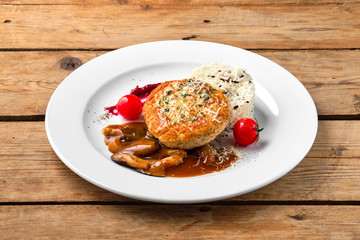Beef cutlet with rice and mushroom sauce on rustic table