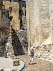 Fototapeta na wymiar Tourist stops to photograph a curved stone road leading between ancient stone buildings in Provence.