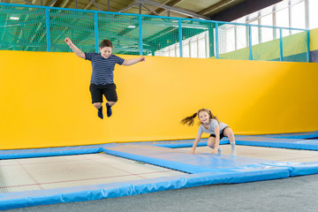Happy smiling small kids jumping on indoors trampoline in entertainment center