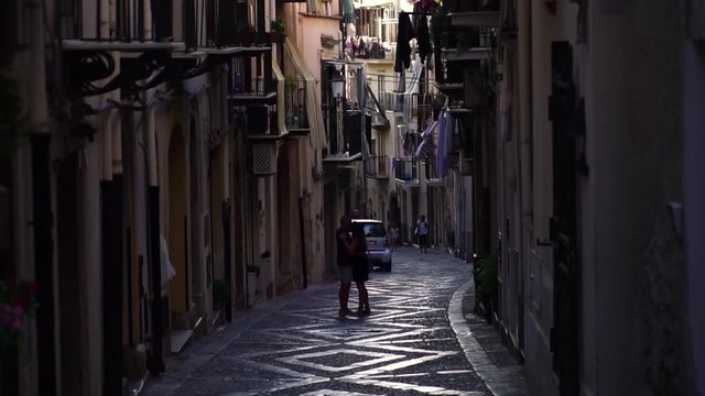 Couple kissing in Cefalu old town street, Sicily, Italy. Picturesque historic town on mediterranean seashore. Summer tourism landmark & family travel destination in Europe.