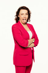 Woman in red suit sticking out her tongue at camera as a sign of disobedience, protest and...