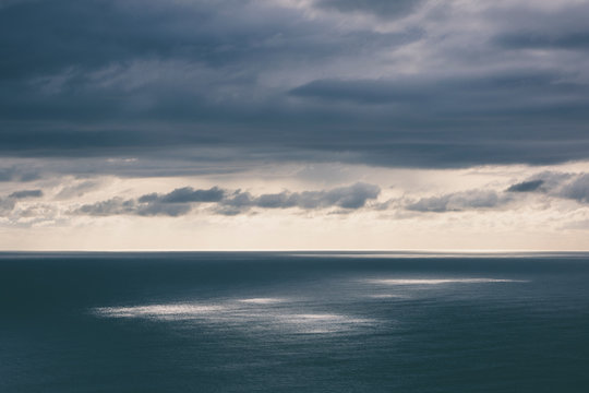 Storm clouds clearing over expansive ocean, dappled sunlight on water, northern Oregon coast,Clearing storm clouds and dappled sunlight on vast ocean at dusk