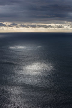Storm clouds clearing over expansive ocean, dappled sunlight on water, northern Oregon coast,Clearing storm clouds and dappled sunlight on vast ocean at dusk