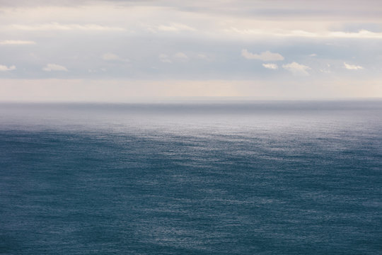 Storm clouds clearing over expansive ocean, dappled sunlight on water, northern Oregon coast,Clearing storm clouds and dappled sunlight on vast ocean at dusk