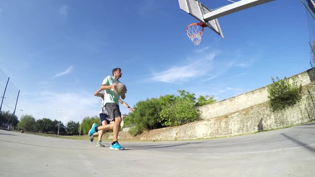 Two guys playing basketball on a clear summer day