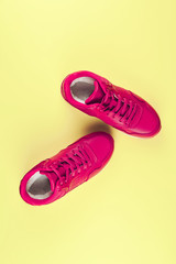 Pink sneakers on yellow background. Concept of sport and healthy lifestyle. Place for text, flat lay, top view, vertical.