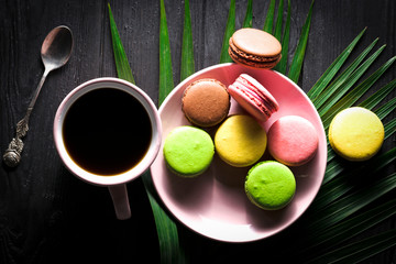 Macaron cookies, cup of espresso on black wooden backdrop