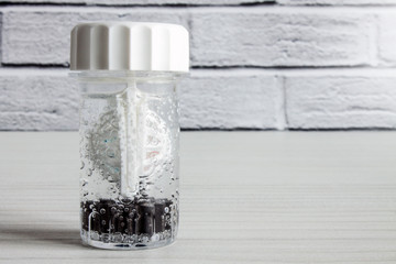 Cleaning and storing hard glass lenses in a container with peroxide liquid on a white background with copy space