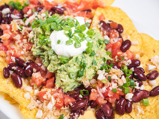 Nachos Traditional Mexican dish. Fresh tasty homemade food for lunch. Balanced and healthy meal. Mexican food nachos with meat beans guacamole and sour creme. Eat healthy at home. 