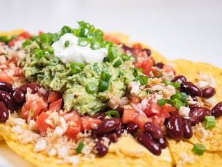 Nachos Traditional Mexican dish. Fresh tasty homemade food for lunch. Balanced and healthy meal. Mexican food nachos with meat beans guacamole and sour creme. Eat healthy at home. 