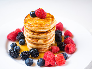 Pancakes for breakfast with raspberries and maple syrup. Fluffy and delicious buttermilk pancakes. Beautiful and healthy fresh food. Home made brunch with berries.