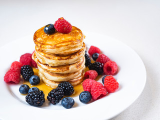Pancakes for breakfast with raspberries and maple syrup. Fluffy and delicious buttermilk pancakes. Beautiful and healthy fresh food. Home made brunch with berries.