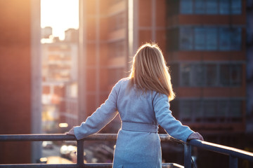 Businesswoman standing on terrace and looking at skyscraper in city