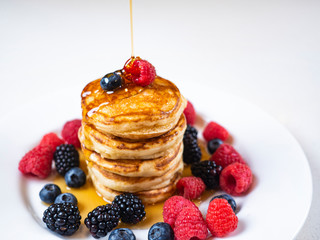 Pancakes for breakfast with raspberries and maple syrup. Fluffy and delicious buttermilk pancakes. Beautiful and healthy fresh food. Home made brunch with berries.