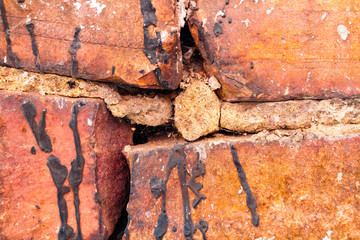 The texture of an old brick wall with patches of cracked and broken cement. Brown broken brickwork...