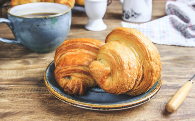 Coffee and croissant on rustic wooden table. French breakfast. Top view. Flat lay. Copy space.