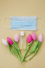 protection during virus outbreak concept: surgical mask and hand sanitizer with artificial spring flowers made from cloth