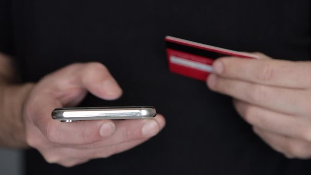 Business Man Guy Paying With Credit Card And His Smartphone. Concept of online payment
