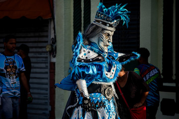 person in bright masquerade costume walks by city street at dominican carnival