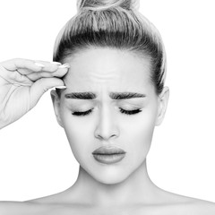 Young sad woman with closed eyes touching skin on forehead.