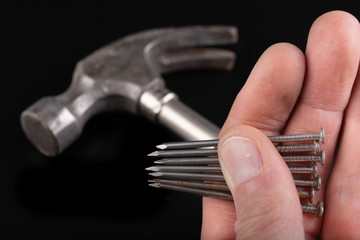 Joiner's hammer and nails held in hands. Carpentry accessories and tools.