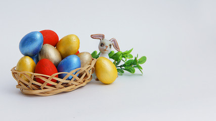colorful Easter eggs in a wicker basket and an Easter Bunny on a white background