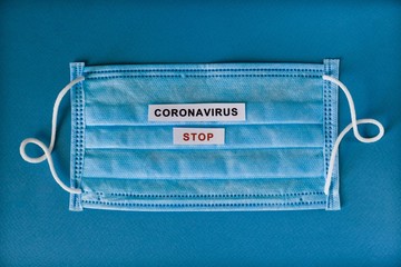 Disposable mask against coronary viral disease 2019 drip infection COVID19. Lies on a blue background with the words Stop Coronavirus