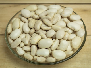 White Beans in a glass plate on a wooden background