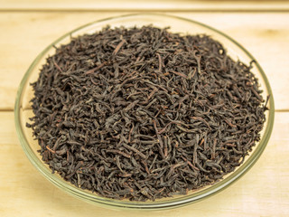 Dry brewed tea in a glass plate on a wooden background