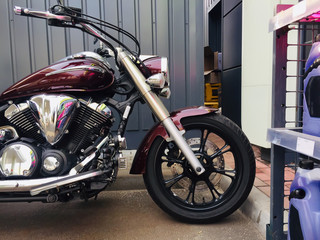 Red cruiser custom motorcycle bike parked at petrol gas station chemicals plastic cans