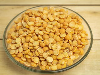 Dry peas in a glass plate on a wooden background