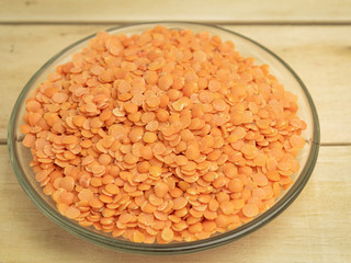 Lentils gray in a glass plate on a wooden background