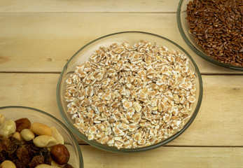 Oatmeal flakes, nuts, butter, milk and flax on a wooden background