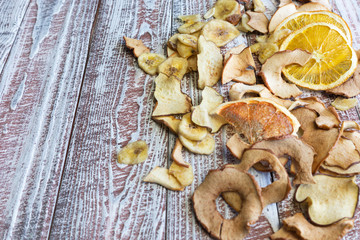 Assorted dried fruits, apple chips, orange chips, on wooden background
