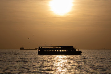 Cruise ship in the middle of the sea at sunset. He retreated in the backlight and towards the sun.