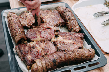 Cooking ribeye steaks and meat rolls in the cooking class. Cooked meat on protwin from the oven,...