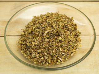 Spices basil in a glass plate on a wooden background