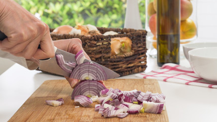 Chopping red onion. Close up on a chopping board, woman hands