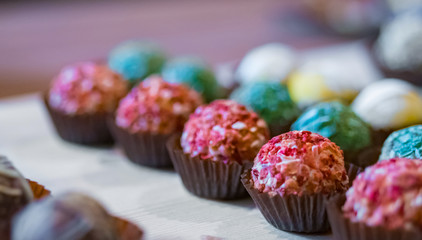 Assortment of colorful delicious fresh truffle cakes for sale on counter of shop, grocery, market, cafe or bakery - close up view. Dessert, sweet food and confectionery concept