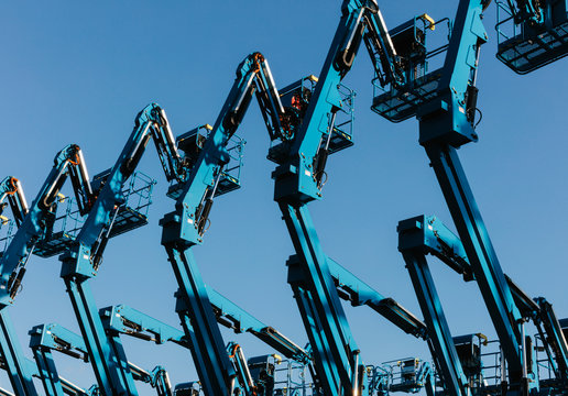 Row of hydraulic mobile cherry picker platforms at outdoor storage facility,Hydraulic cranes