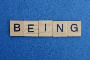  word being from small gray wooden letters lies on a blue background