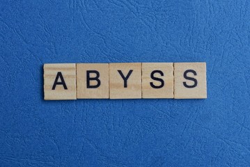 word abyss from small gray wooden letters lies on a blue background