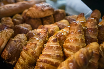 Assortment of freshly baked croissants for sale on counter of shop, market, cafe or bakery. Dessert, pastry, breakfast, sweet food and traditional french cuisine concept