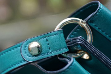 green leather harness on bag with yellow metal rivet and carabiner ring