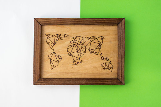 Wooden picture with the image of a world map made using the technique of pyrography and decorated with a carved frame - Powered by Adobe