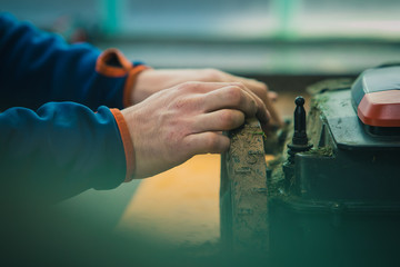 Serviceman stripping robotic lawnmower, motorized lawnmower being serviced on a table after a year of use in the mud and grass. Regular maintenance of robotic lawnmower