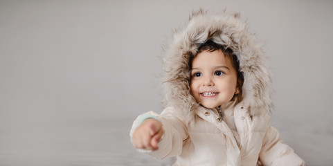 Happy little child girl in white down jacket