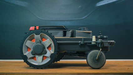 Clean side view of robotic lawnmower, motorized lawnmower being serviced on a table after a year of...