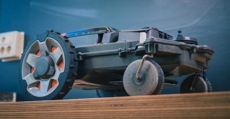 Clean side view of robotic lawnmower, motorized lawnmower being serviced on a table after a year of...