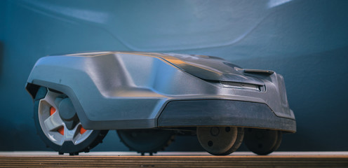 Clean side view of robotic lawnmower, motorized lawnmower being serviced on a table after a year of use in the mud and grass. Regular maintenance of robotic lawnmower
